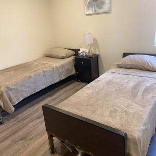 A minimalist bedroom with two twin beds and a nightstand.