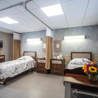 A clean and well-organized hospital room with two beds and floral decoration.