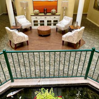 A cozy lobby area with plush chairs and a central coffee table, overlooking an indoor pond.