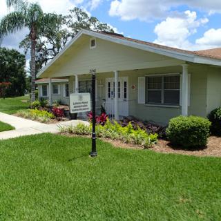 A charming residential building surrounded by lush greenery and colorful landscaping.
