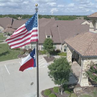 The flags of the United States and Texas flying proudly in front of a residential building.