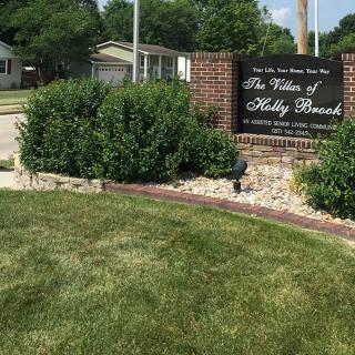 A town entrance sign surrounded by greenery and landscaping.