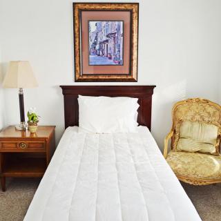 A simple bedroom with a single bed, nightstand, and framed artwork on the wall.