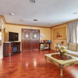 A cozy living room featuring a wooden floor, a comfortable sofa, and a television.
