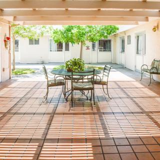 A peaceful courtyard with a tiled patio featuring outdoor seating and dappled sunlight.