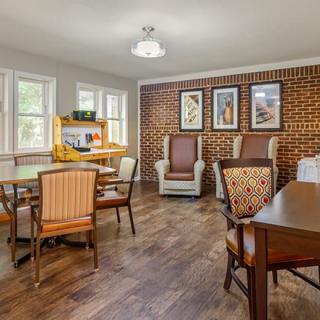 A cozy living room with a mix of armchairs, wooden furniture, and a brick accent wall.