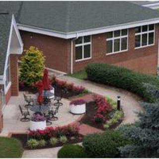 An aerial view of a landscaped garden with outdoor seating and a brick building in the background.