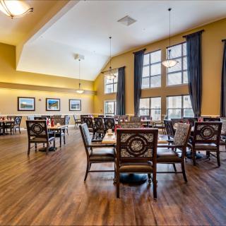 A spacious dining area with elegant tables and chairs, featuring large windows and warm lighting.