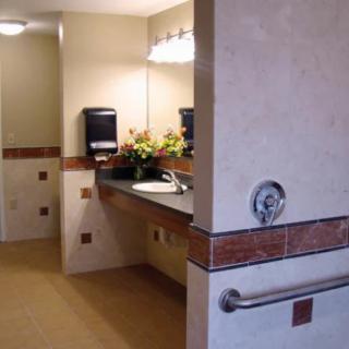 A clean and well-lit bathroom with a sink, mirror, and decorative flowers.