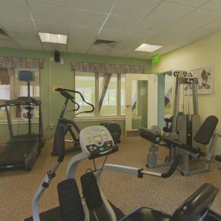 A small gym with various exercise equipment, including treadmills, stationary bikes, and weight machines.