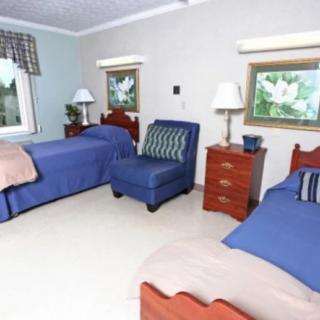 A cozy bedroom with two twin beds featuring blue bedding, a comfortable armchair, and matching lamps on nightstands.