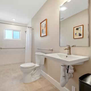 A modern and minimalist bathroom with a large mirror, sink, and toilet.