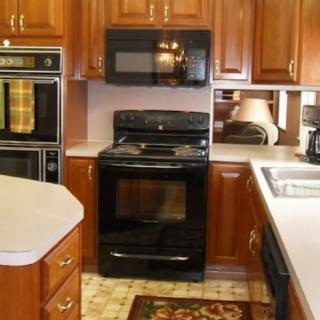 A kitchen featuring wooden cabinets, a black oven, and a microwave.