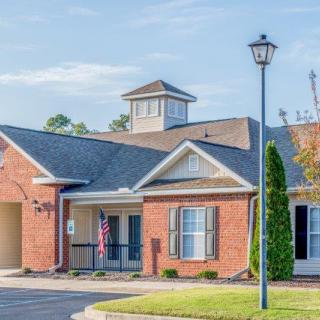 A suburban brick house with a driveway and a lamp post in the front yard.