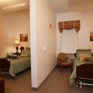 A shared bedroom with two hospital-style beds separated by a wall, featuring simple decor and cozy lighting.