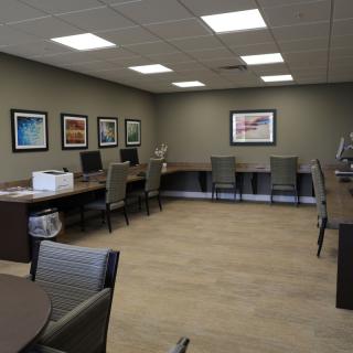 A modern office space with computers, chairs, and wall art.