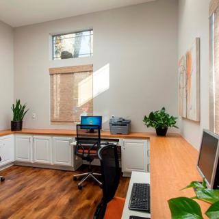 A modern home office with a spacious desk, computer setup, and natural lighting.