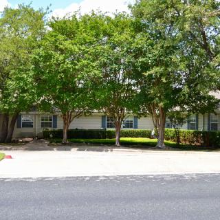 A suburban house surrounded by trees and landscaping.