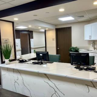 A modern reception area featuring a sleek white marble countertop and green accents.