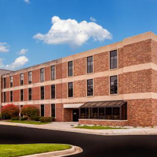 A modern brick building with large windows under a clear blue sky.
