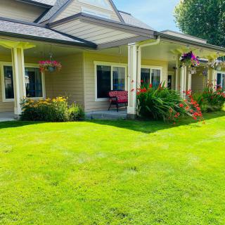 A charming house with a well-maintained lawn and garden, featuring colorful flowers and a welcoming porch.
