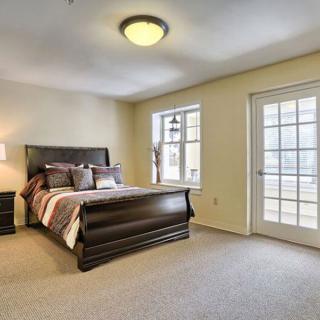 A comfortable and spacious bedroom with a large window and glass door leading to the outside.