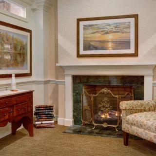 A cozy living room with a fireplace, artwork on the walls, and elegant furniture.