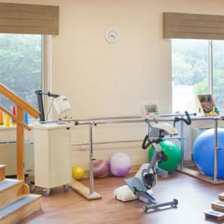 A physical therapy room with various rehabilitation equipment, including parallel bars and exercise balls.