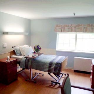 A clean and well-lit hospital room with a bed, side table, and a window.