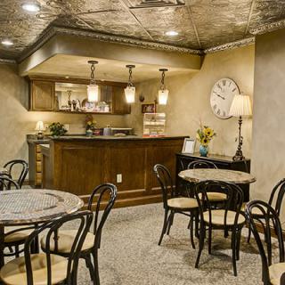 A cozy cafe interior with tables, chairs, and a well-lit bar area.