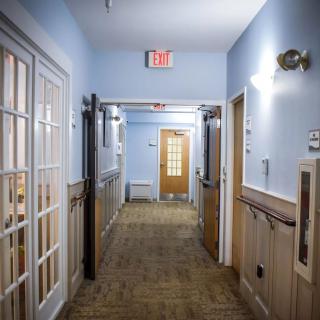 A well-lit building hallway with multiple doors and an exit sign.