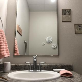 A bathroom with a sink, mirror, and neatly arranged towels.