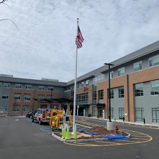 A modern building with an American flag in front, under a cloudy sky.