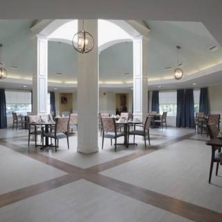 A modern and spacious dining area with elegant lighting fixtures and neatly arranged tables and chairs.