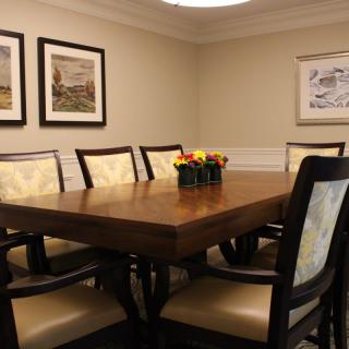 A cozy dining room with a wooden table surrounded by chairs and adorned with artwork on the walls.