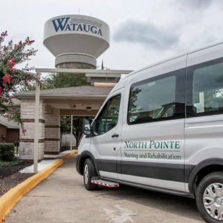 A van parked in front of a building with a water tower labeled 'Watauga' in the background.