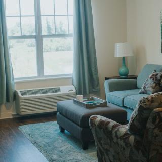 Cozy living room with a sofa, armchair, and a large window letting in natural light.