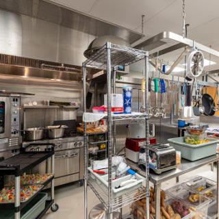 A well-equipped industrial kitchen with stainless steel surfaces and organized shelves filled with cooking equipment and utensils.