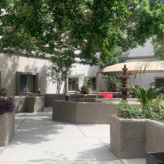 A tranquil courtyard with lush greenery, featuring a fountain and outdoor seating.