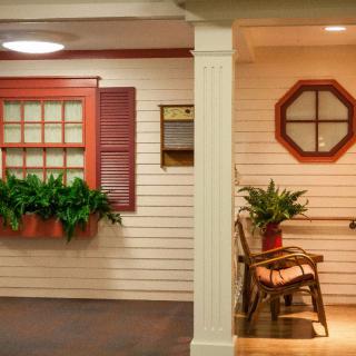 A cozy indoor space with a window-style decor, potted plants, and a rocking chair.