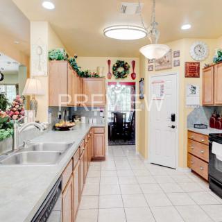 A bright and modern kitchen adorned with holiday decorations, featuring wood cabinets and a tile floor.