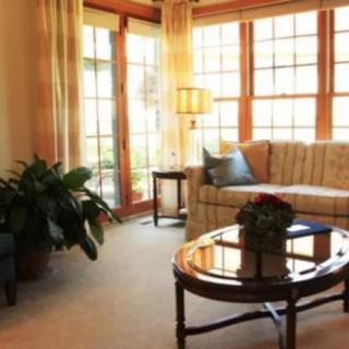 A cozy living room with large windows, a sofa, and a coffee table.