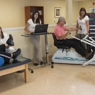 A rehabilitation center where patients are engaging in physical therapy exercises with the assistance of healthcare professionals.