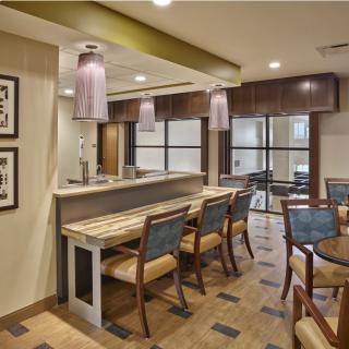 A modern cafe interior with a bar and seating area featuring wooden furniture and decorative lighting.