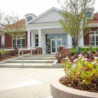 A well-maintained building entrance with landscaped flower beds and steps leading to the door.