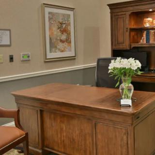 A well-organized office space featuring a wooden desk and chair, with flowers as decoration.
