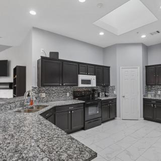 A modern kitchen featuring dark cabinets, granite countertops, and recessed lighting.