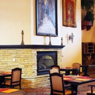 A cozy restaurant interior featuring a stone fireplace and neatly arranged tables and chairs.
