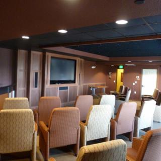A cozy conference room with arranged seating facing a large screen.