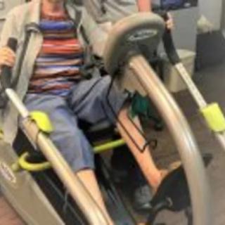 A person using a recumbent exercise machine indoors.